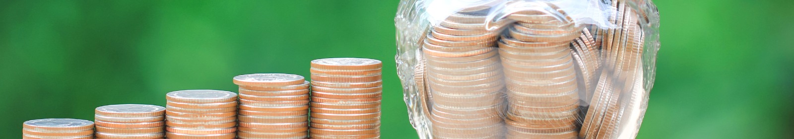 a jar full of coins beside a five stacks of coins