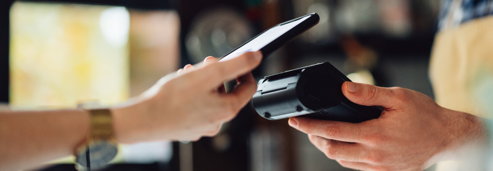 Close-up of a hand holding a smartphone up to a card reader