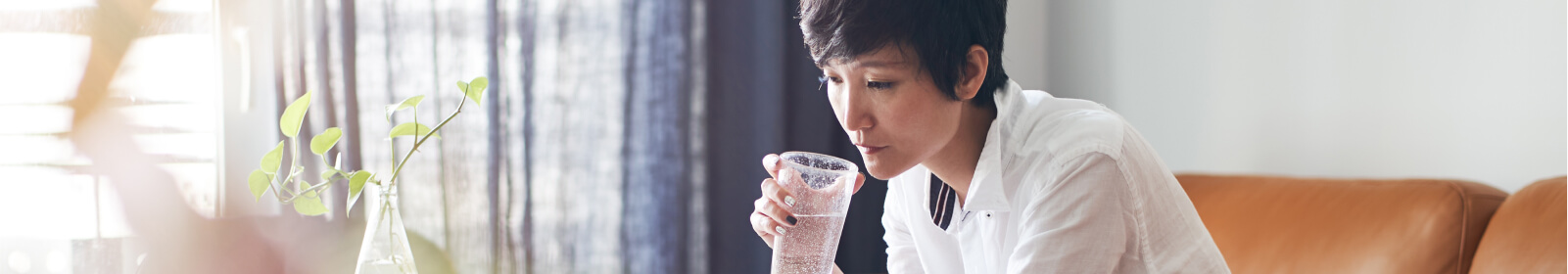 a woman drinking a glass of water looking at her laptop